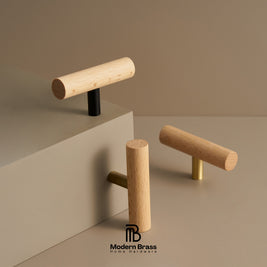 Three modern cylindrical wood cabinet knobs with different metal base accents (black, gold, and brass) displayed on a minimalist beige geometric set. The Modern Brass logo is visible at the bottom.