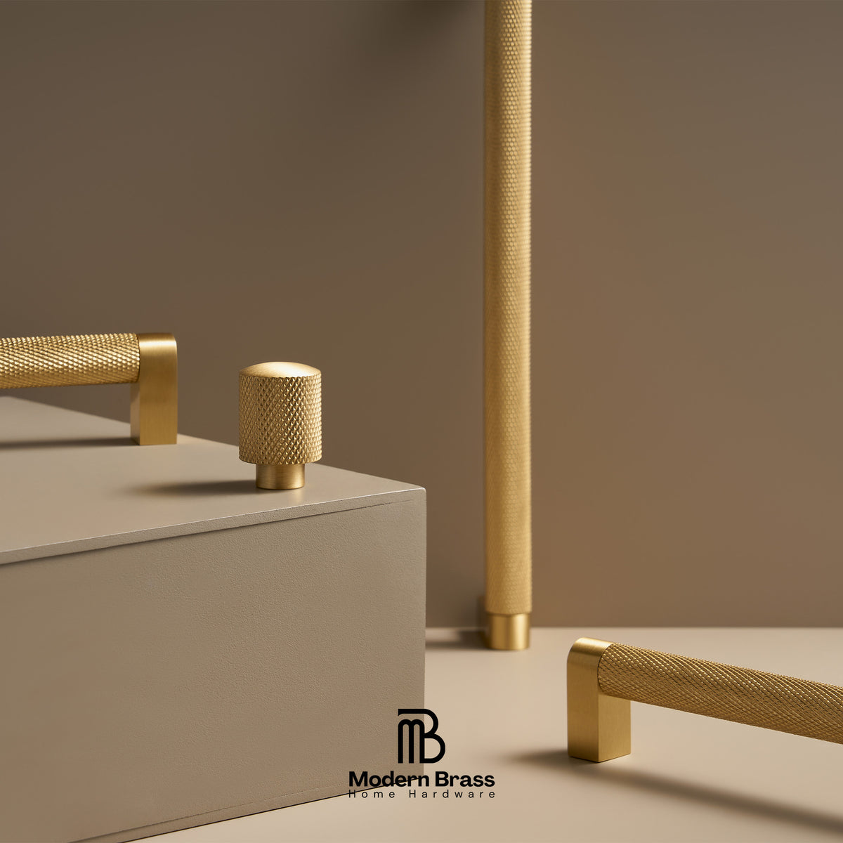 Modern brass home hardware set including textured cylindrical knobs and bar pulls in a warm brushed gold finish, displayed on a minimalist beige background with a geometric pedestal.